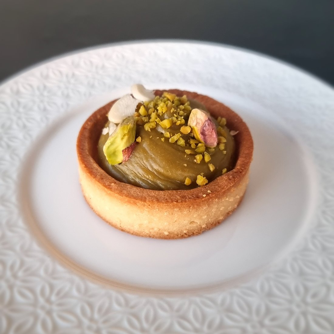 Tartelletta con crema di pistacchio su piatto bianco